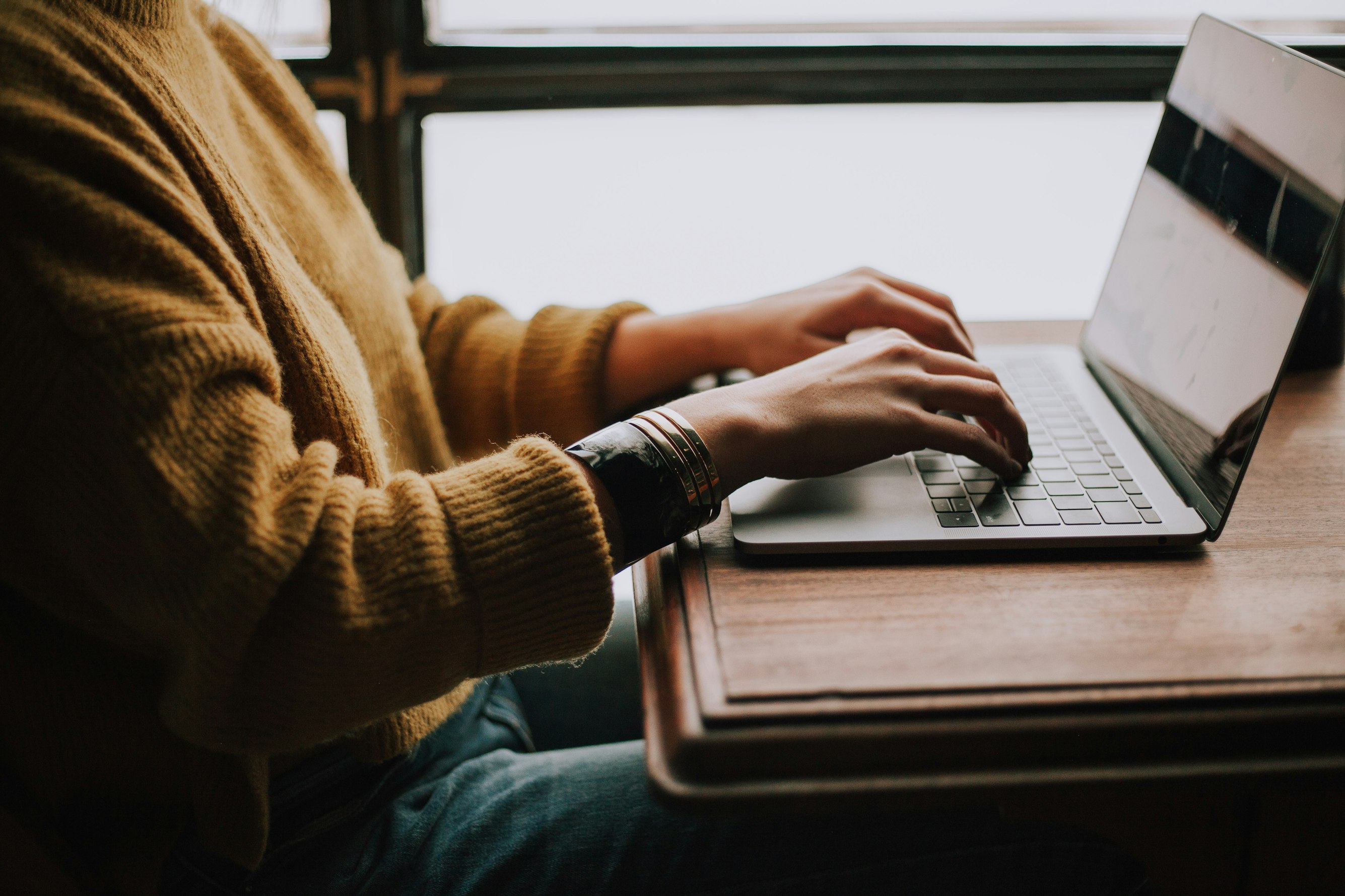 Person tippt an Laptop von der Seite